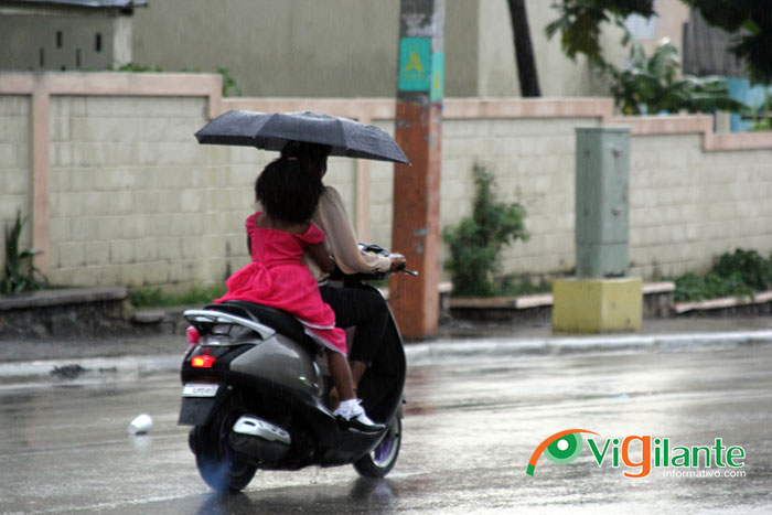 Bajo la lluvia, una mujer y una niña se desplazan en una pasola por una calle de Elías Piña, dónde las precipitaciones se han vuelto frecuentes en los últimos días. (Foto: Genris García)